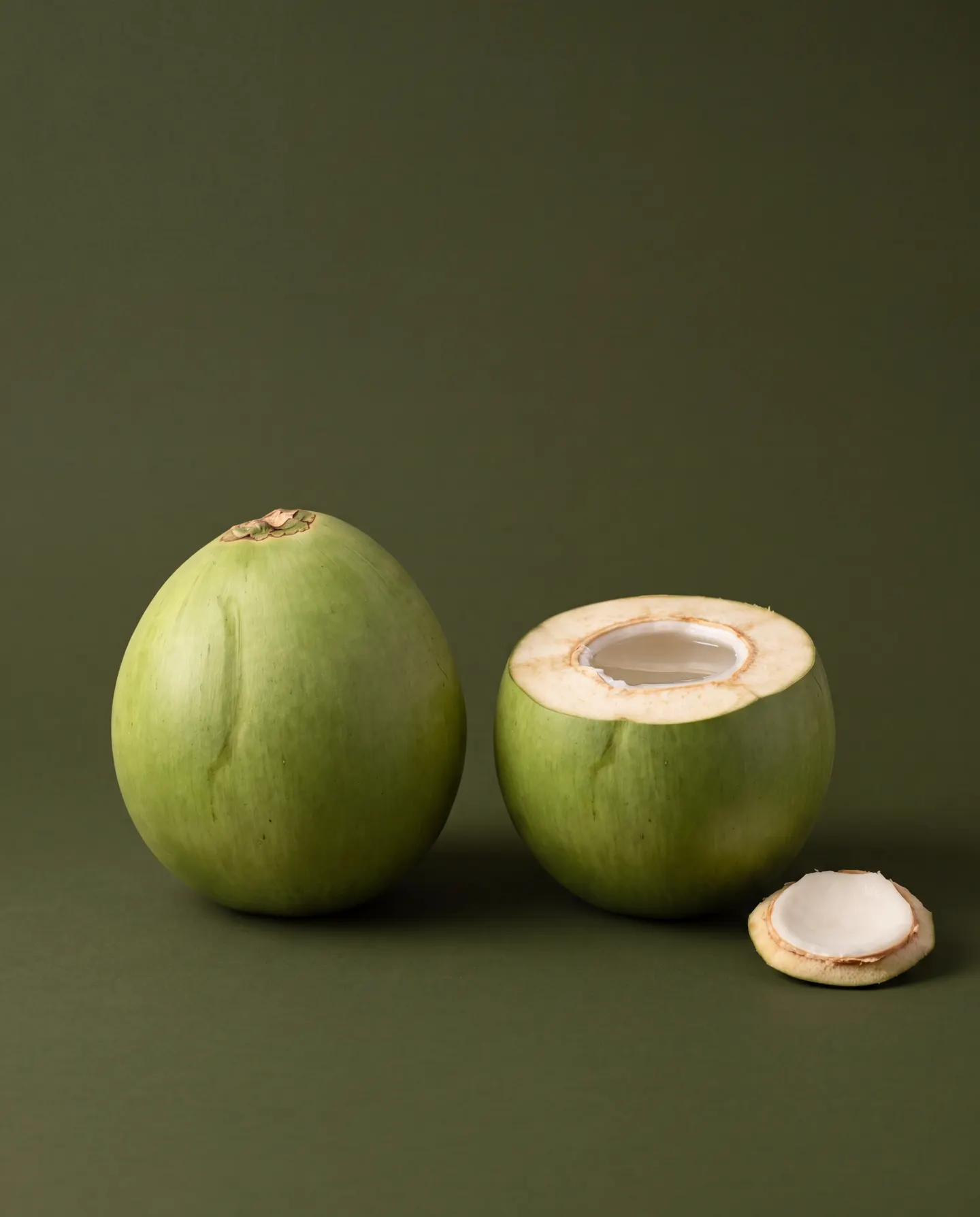 Coco cortado ao meio, com a água translúcida e a polpa branca fina junto à casca.